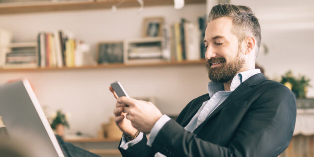 homme barbu utilisant un smartphone dans un bureau à domicile