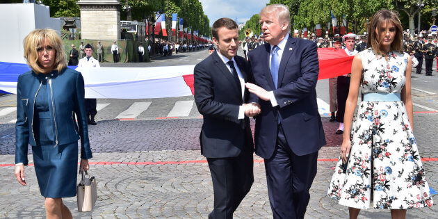 French President Macron shakes hands with US President Trump next to Macron's wife Brigitte Macron and US First Lady Melania Trump during the traditional Bastille Day military parade in Paris