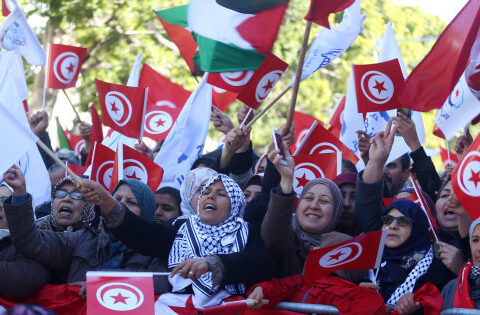 People wave national flags during demonstrations on the seventh anniversary of the toppling of president Zine El-Abidine Ben Ali, in Tunis