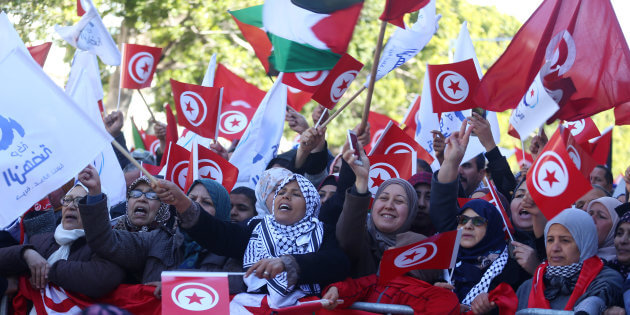 People wave national flags during demonstrations on the seventh anniversary of the toppling of president Zine El-Abidine Ben Ali, in Tunis