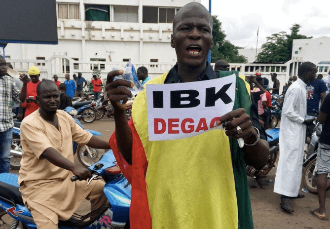 Un partisan de l'opposition tient une pancarte indiquant "IBK (président Ibrahim Boubacar Keita) dégage''