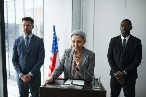 Femme prononçant un discours avec des gardes du corps derrière elle