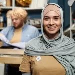Femme en hijab gris souriant.